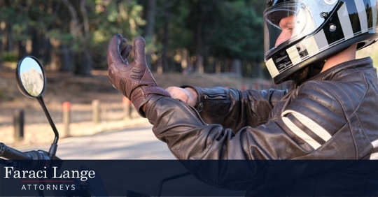 person sitting on a motorcycle wearing a helmet and leather jacket putting on gloves