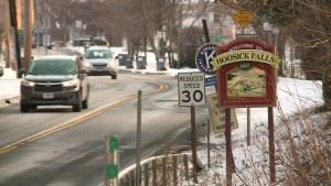 Cars driving down a road in the winter with snow on the sides of the road