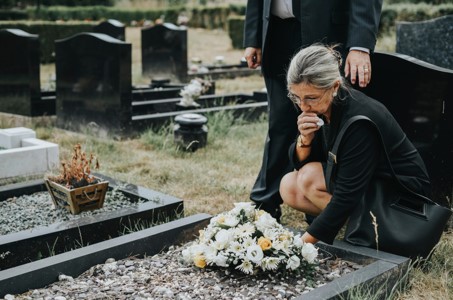 woman kneeling at the graveside of a deceased loved one after a wrongful death attorney